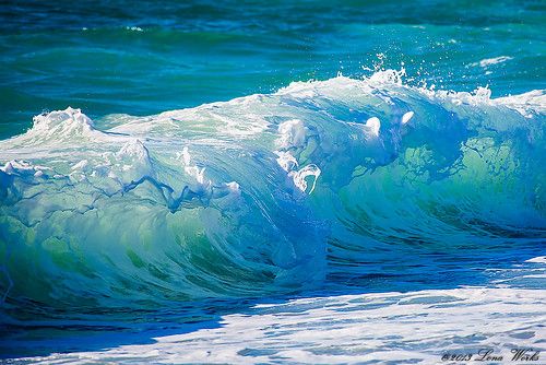 an ocean wave breaking on the beach with bright blue water and white foamy waves