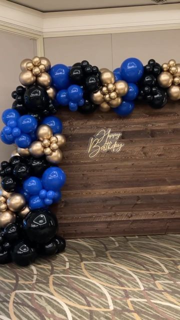 a wooden box with black and gold balloons in it on a carpeted room floor