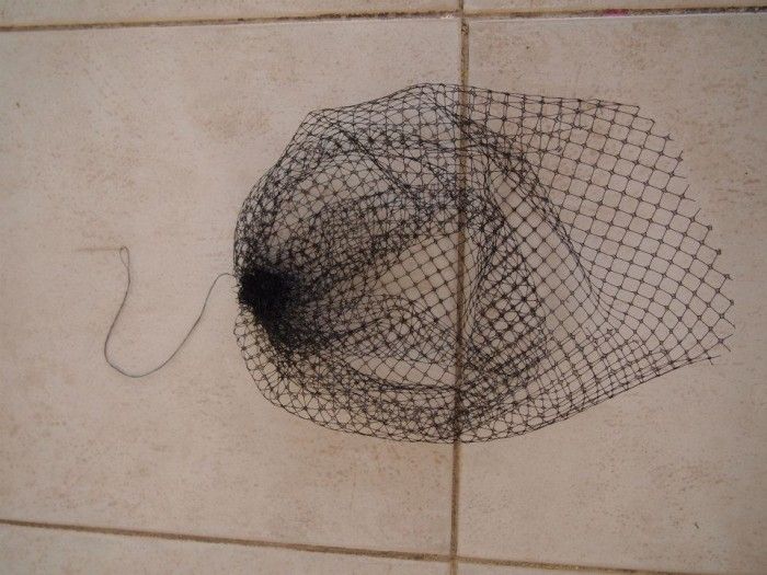 a piece of black net sitting on top of a tile floor next to a wall