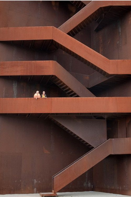 two teddy bears are sitting on the ledges of a tall building that is made of metal