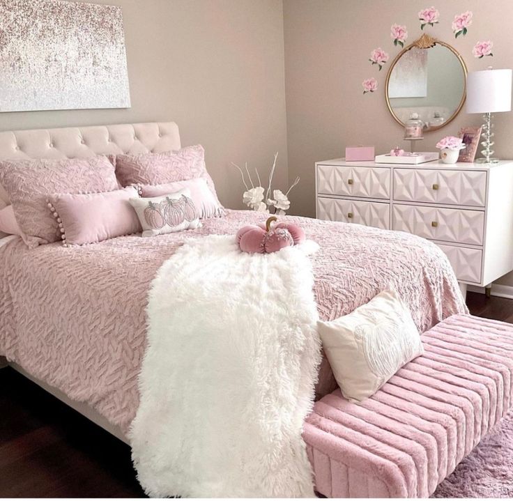 a bedroom with pink bedding and white fur on the headboard, dressers and mirror