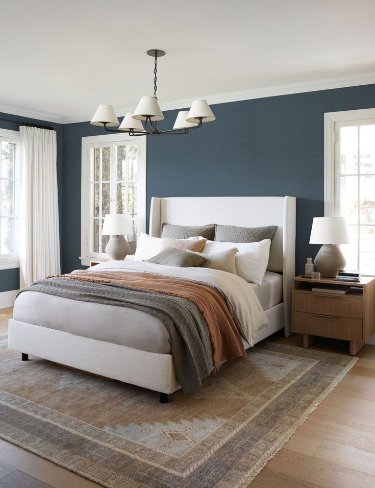 a bedroom with blue walls and white bedding, two lamps on either side of the bed