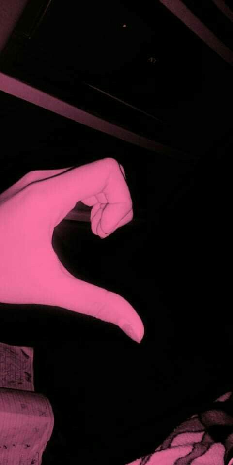 a person's hand pointing at something in the air with pink light on it