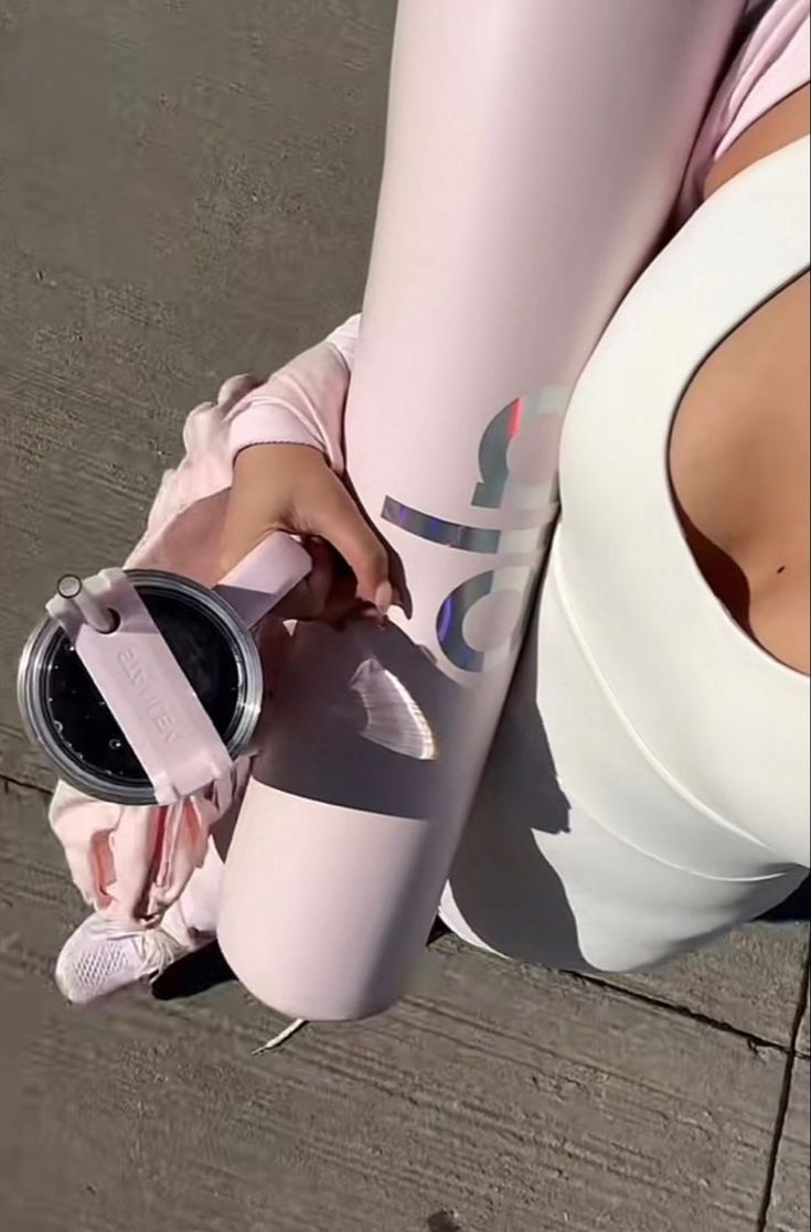 a woman in pink sports bra and leggings holding a water bottle with her right hand