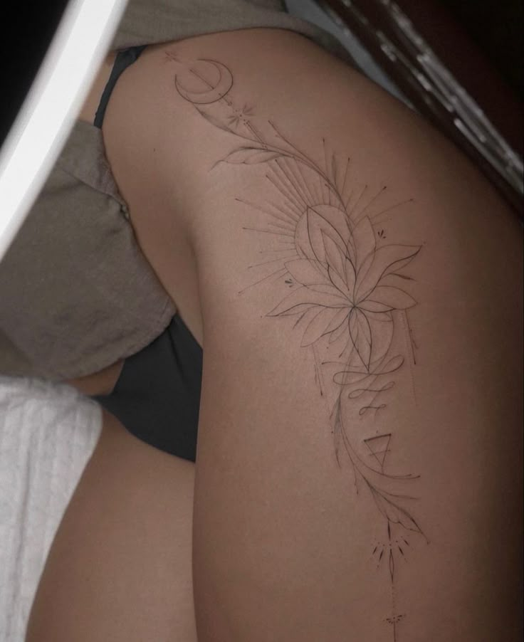 a woman laying in bed with her back turned to the camera and tattoos on her thighs