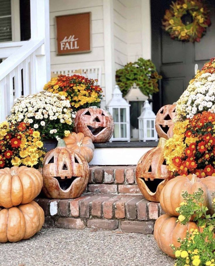 some pumpkins are sitting on the front steps with flowers and plants in their heads