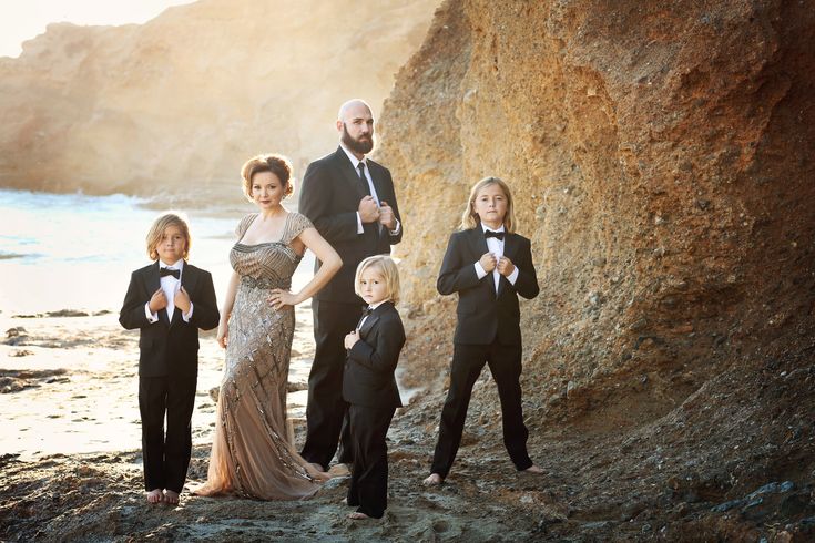 a group of people standing next to each other on a rocky beach near the ocean