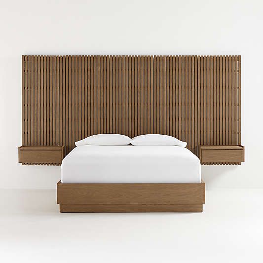 a bed with white sheets and pillows in front of a wooden headboard that has bamboo slats on it