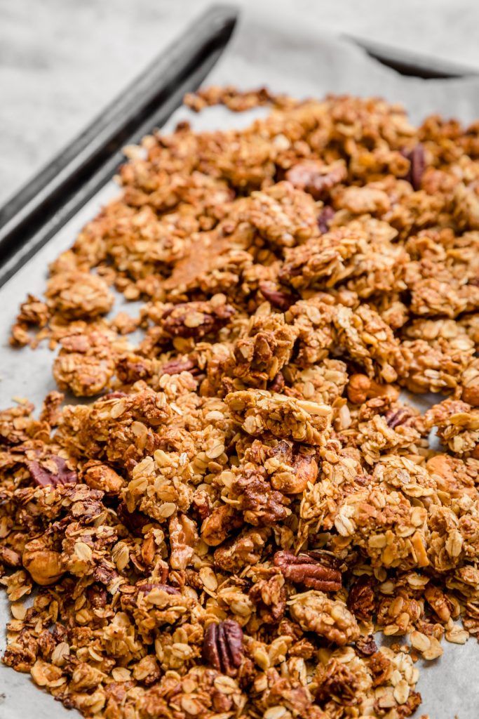 granola on a baking sheet with two black spoons