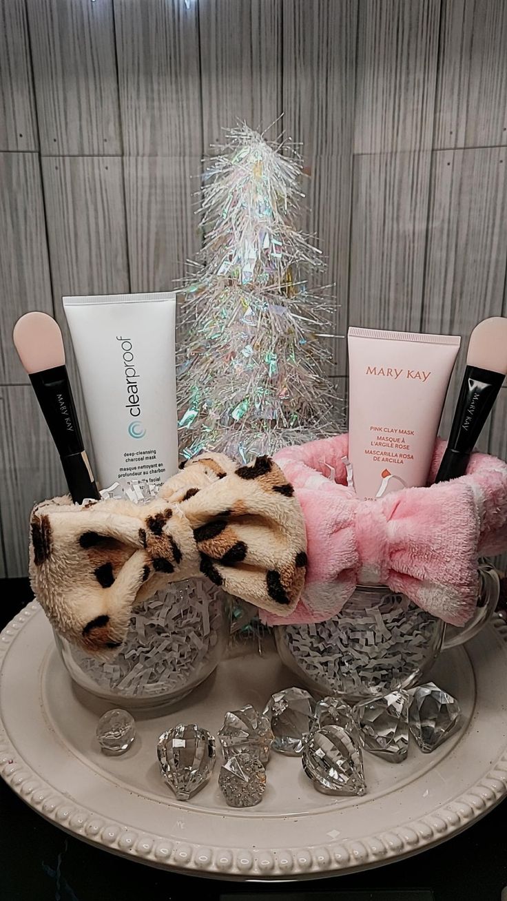 a white plate topped with makeup and other items next to a christmas tree on a table