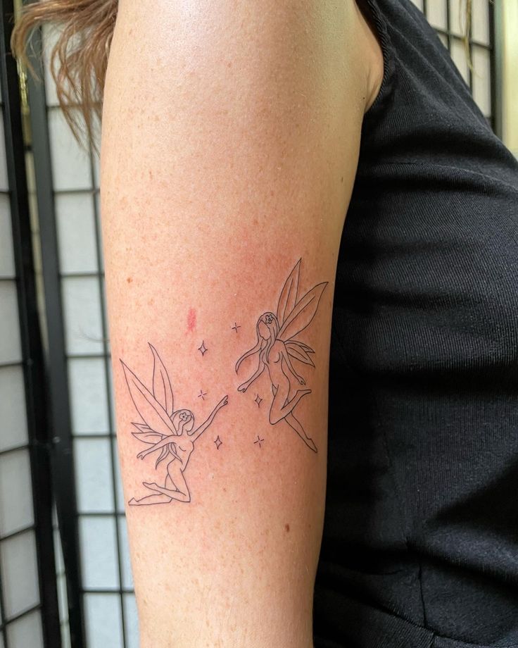 a woman with a tattoo on her arm that has tinkerbells drawn on it