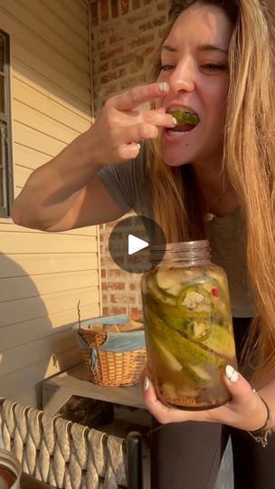 a woman eating pickles out of a jar