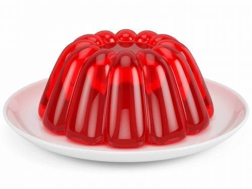 a red jelly bundt cake on a white plate with the bottom half covered in icing