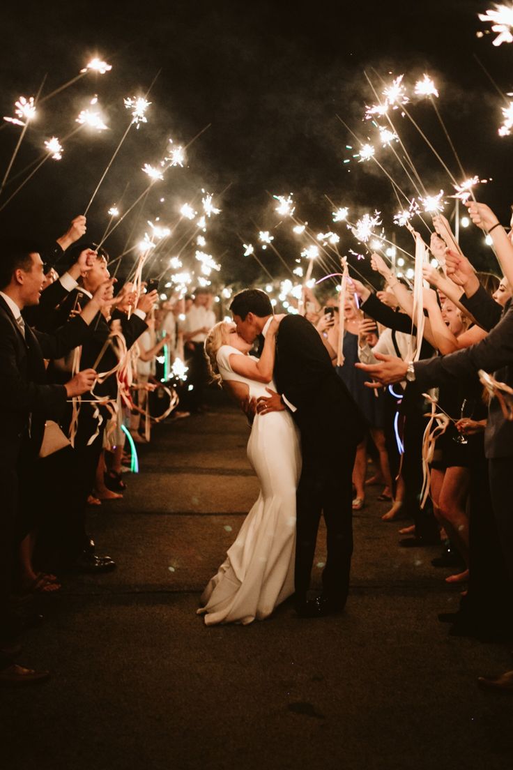 a newly married couple kissing under sparklers