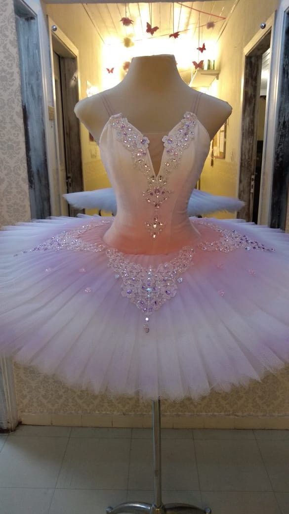 a pink and white ballerina dress sitting on top of a mannequin