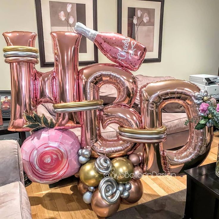 large pink and gold balloon letters are displayed on a coffee table