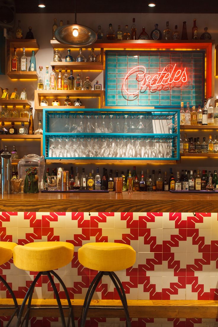 two yellow stools sitting in front of a bar