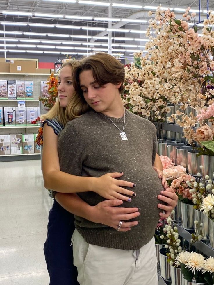 a pregnant woman hugging her husband in a flower shop