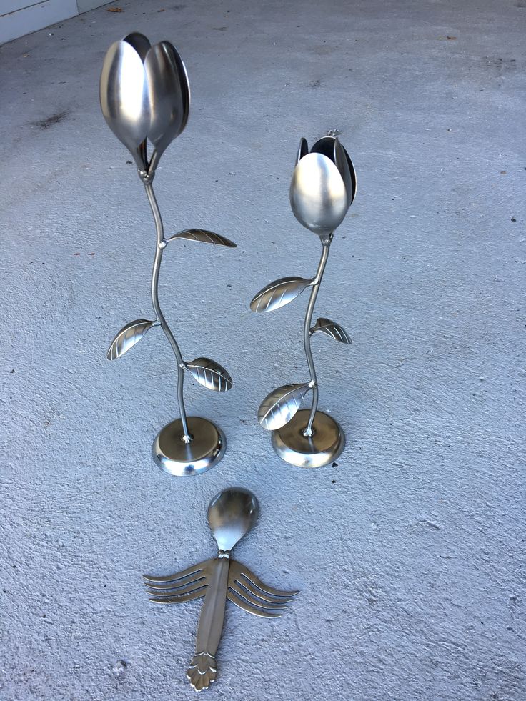 three spoons and two forks are arranged in the shape of flowers with leaves on them