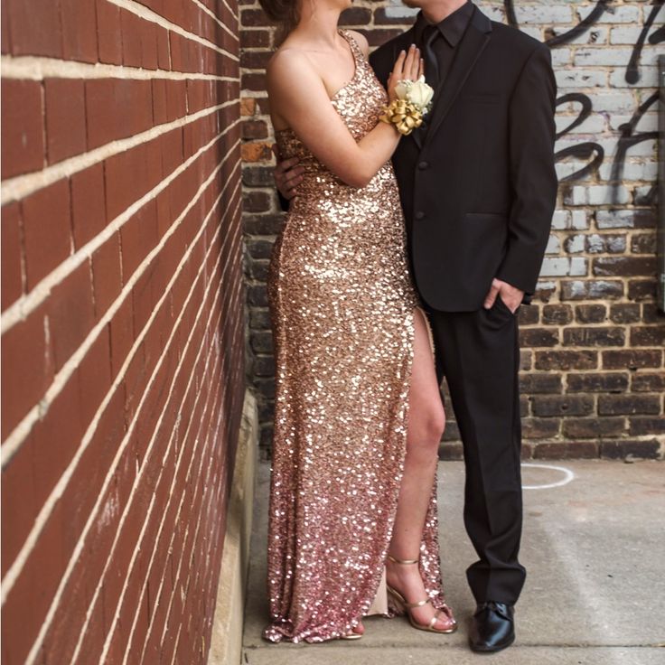 a man and woman standing next to each other in front of a brick wall