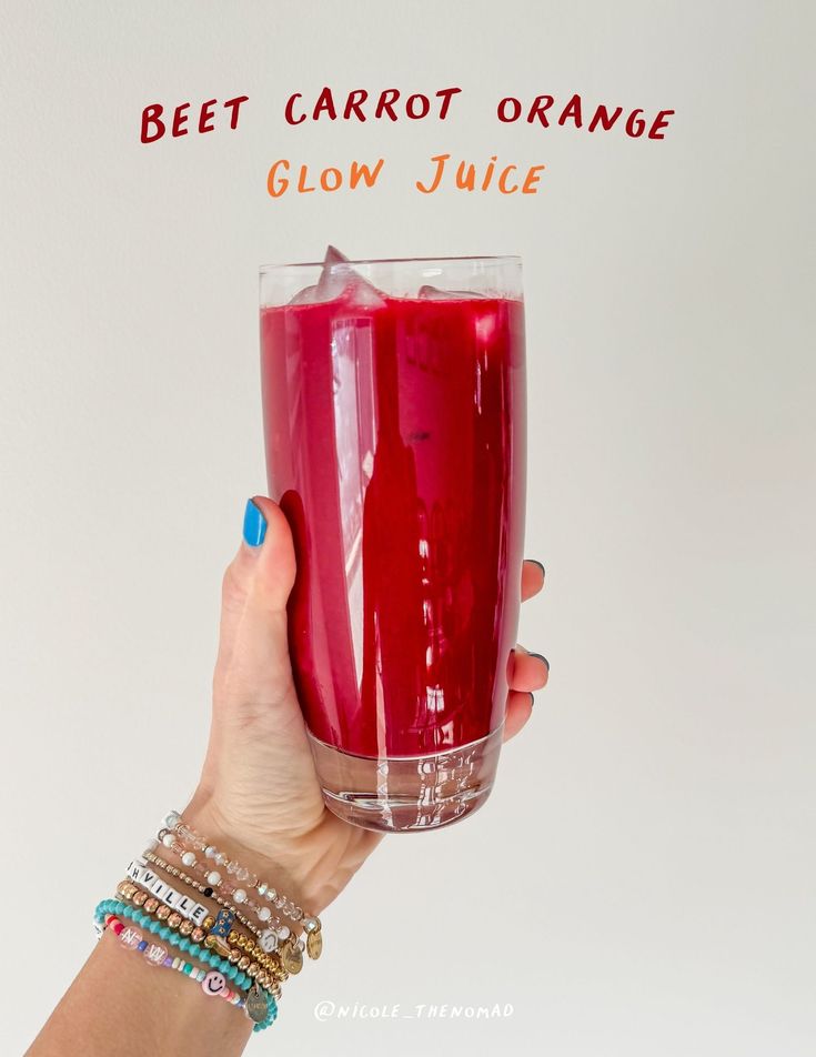 a woman holding up a glass filled with juice and the words beet carrot orange glow juice