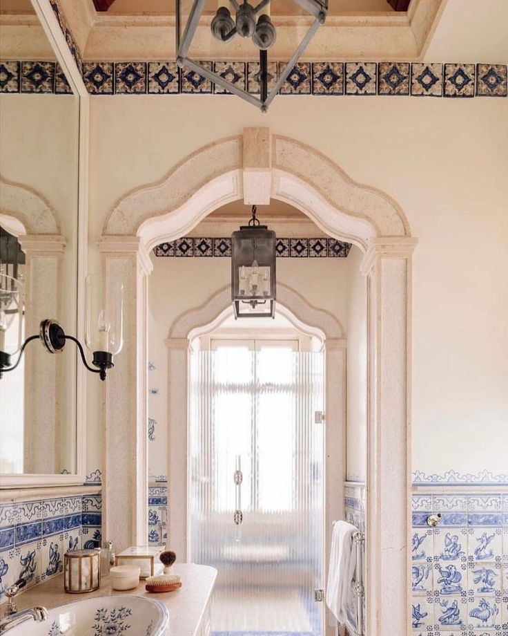 a bathroom with blue and white tiles on the walls, an arched doorway leading to another room