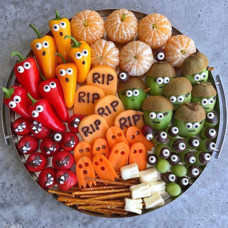 a platter filled with oranges, peppers and other food items that have eyes on them