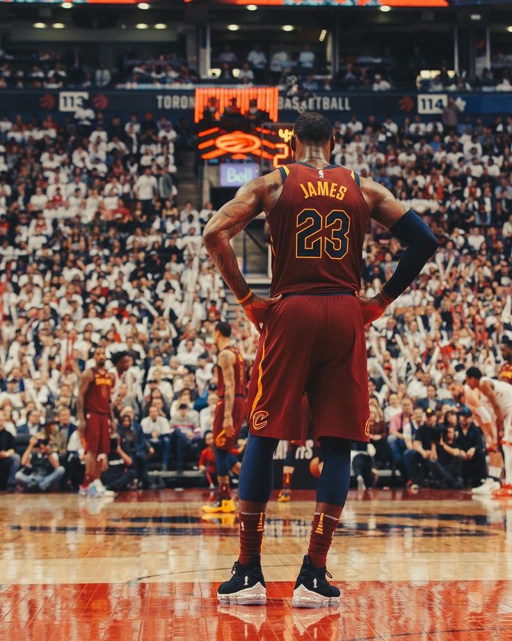 a man standing on top of a basketball court in front of an arena full of people