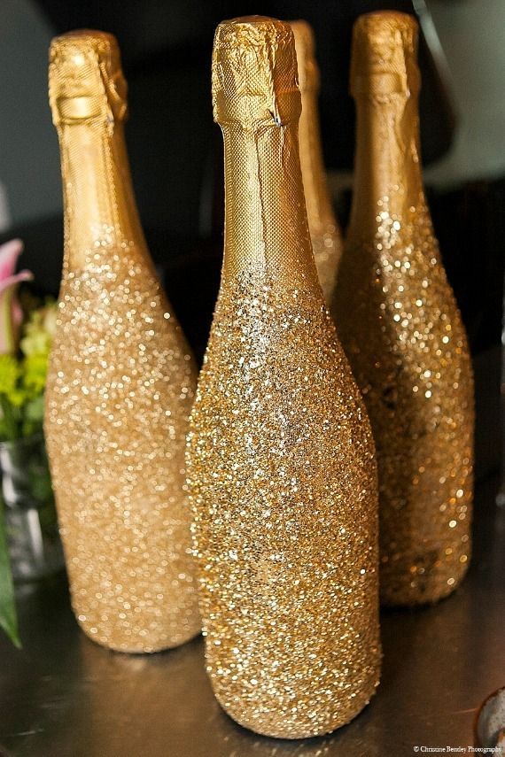 three champagne bottles sitting on top of a table covered in gold flecks and glitter