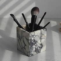 a marbled container with brushes in it on a white table next to a teddy bear