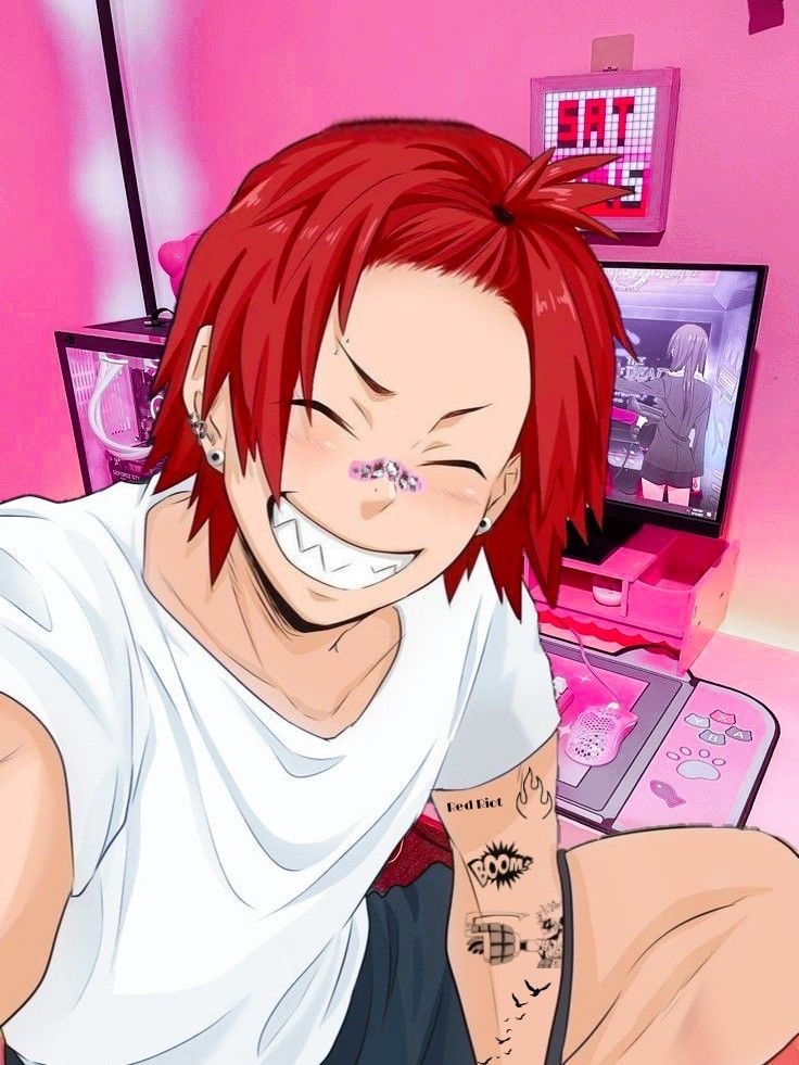 a man with red hair and piercings sitting in front of a laptop computer