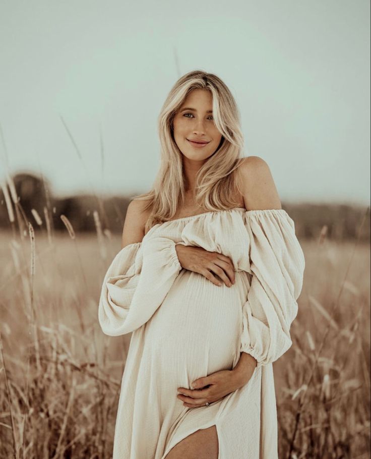 a pregnant woman poses for a photo in a field