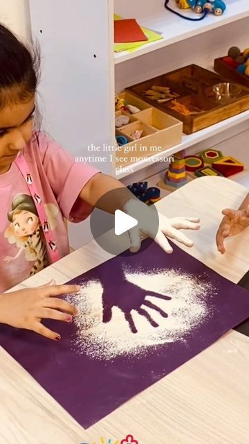 two children are making handprints out of white powder on a purple mat with their hands