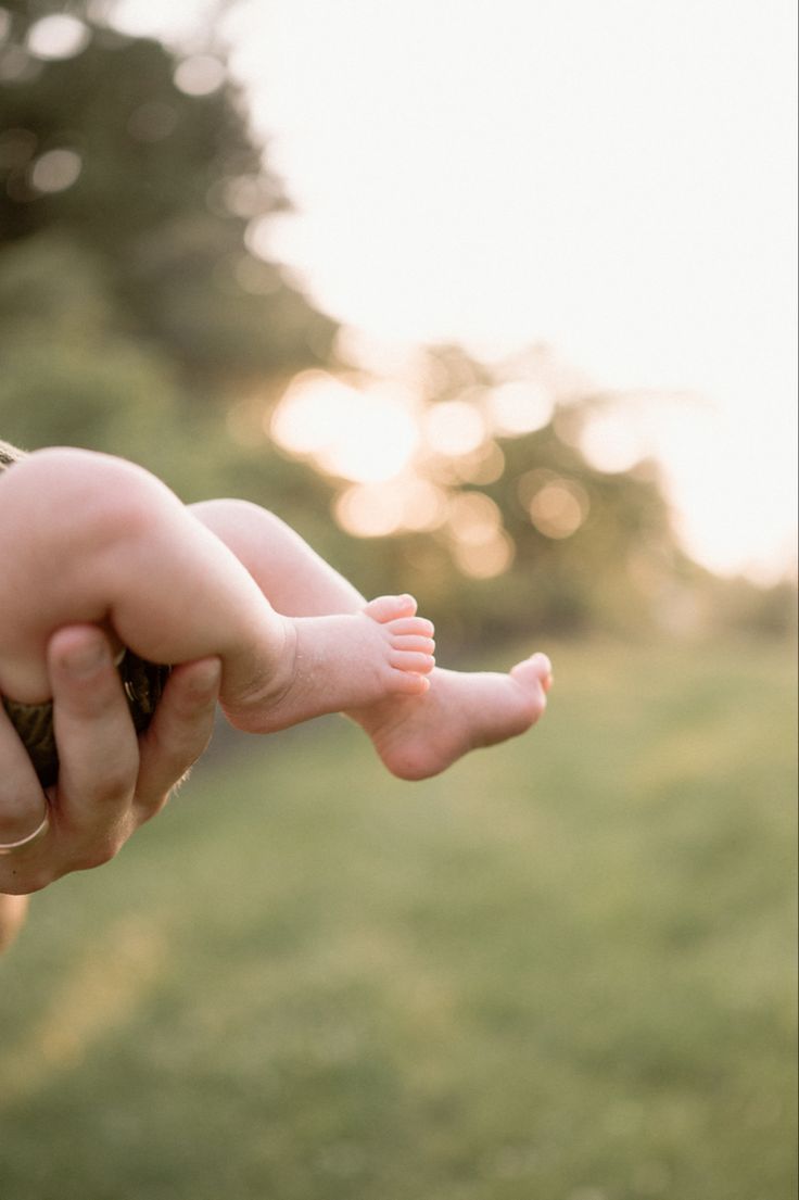 a woman holding a baby in her arms while she holds it up to the camera