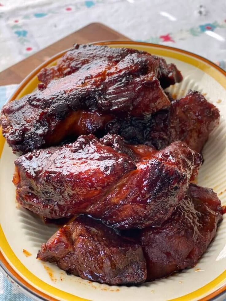 two pieces of meat on a yellow and white plate