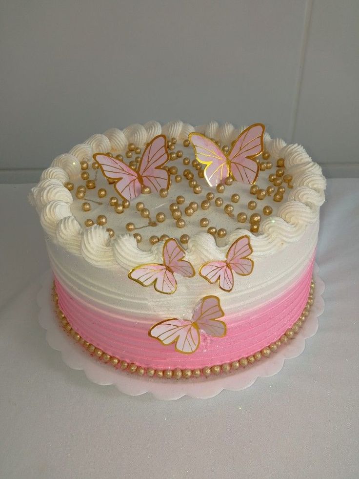 a cake with white frosting and pink icing decorated with gold butterflies on top