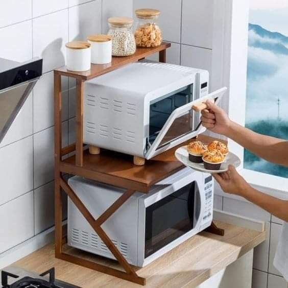 a person holding a plate with food in front of a microwave