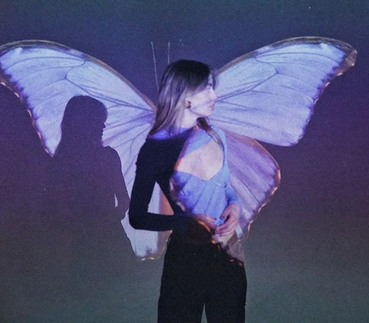 a woman standing in front of a purple and white butterfly costume with wings on her back