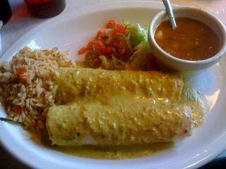 an enchilada with rice and salsa on a white plate