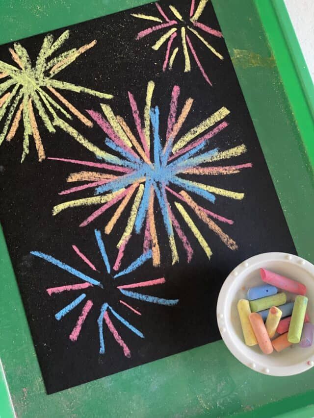 chalk crayons are placed on a blackboard with colorful fireworks