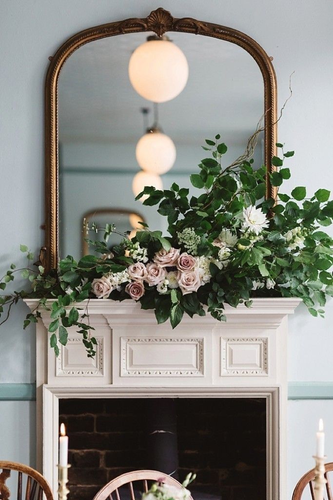 the fireplace is decorated with flowers and greenery for an elegant touch to the room