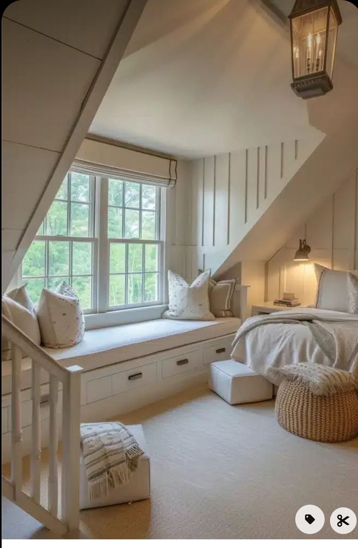 an attic bedroom with white walls and carpeted flooring, built - in storage drawers, window seat, and bench