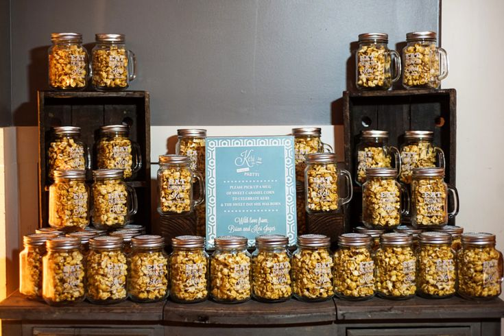 there are many jars full of food on the shelf next to each other with a sign