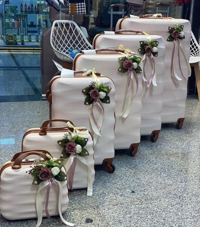 four pieces of luggage with ribbons and flowers on them sitting in front of an airport lobby