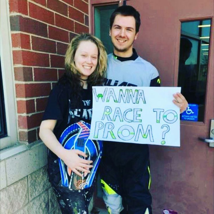 a man and woman standing next to each other holding a sign that says wanna race to prom