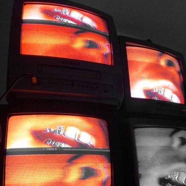 three televisions with faces on them are shown in black and white, one is red