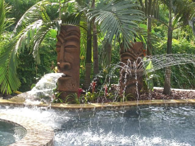 an outdoor fountain with water coming out of it and palm trees in the back ground