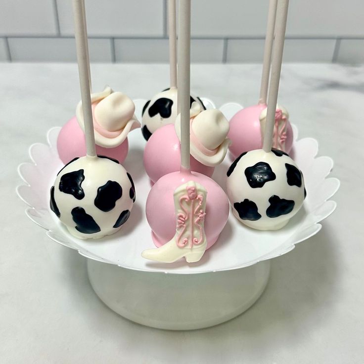 cake pops decorated with pink and white frosting on top of a plate in the shape of soccer balls