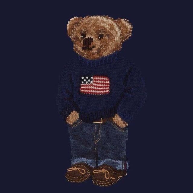 a teddy bear wearing a blue sweater with an american flag on it's chest