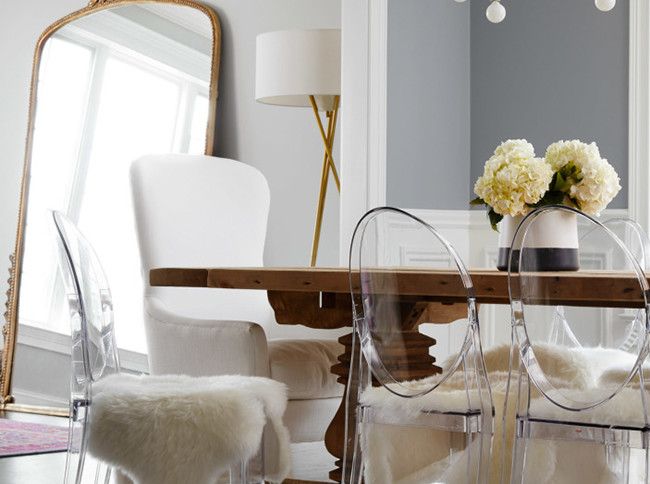 a dining room table with chairs and flowers on the top one chair is made out of clear acrylic